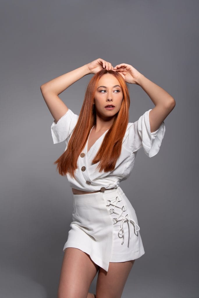Modelo pelirroja con conjunto blanco posando en estudio