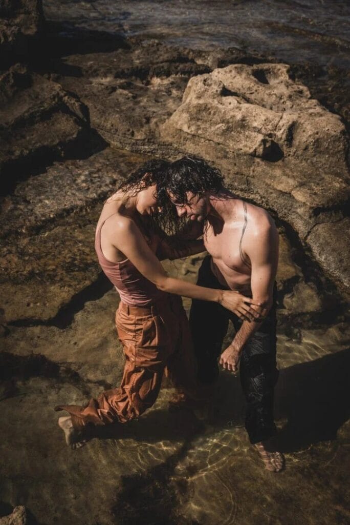 Pareja de bailarines abrazados entre rocas en una sesión de performance