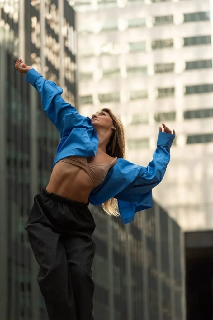 Bailarina con camisa azul en movimiento frente a un edificio de cristal en Palma