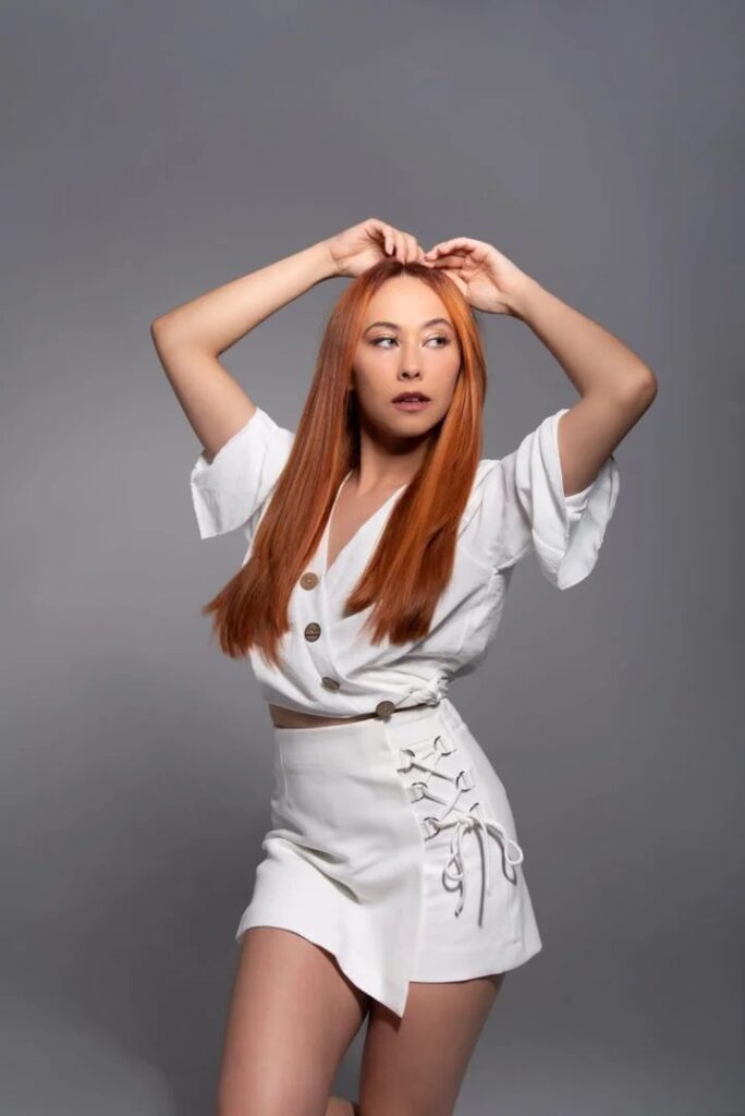 Modelo pelirroja con conjunto blanco posando en estudio