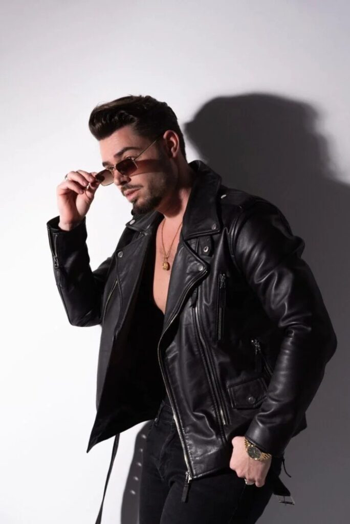 Modelo masculino con chaqueta de cuero y gafas de sol en estudio