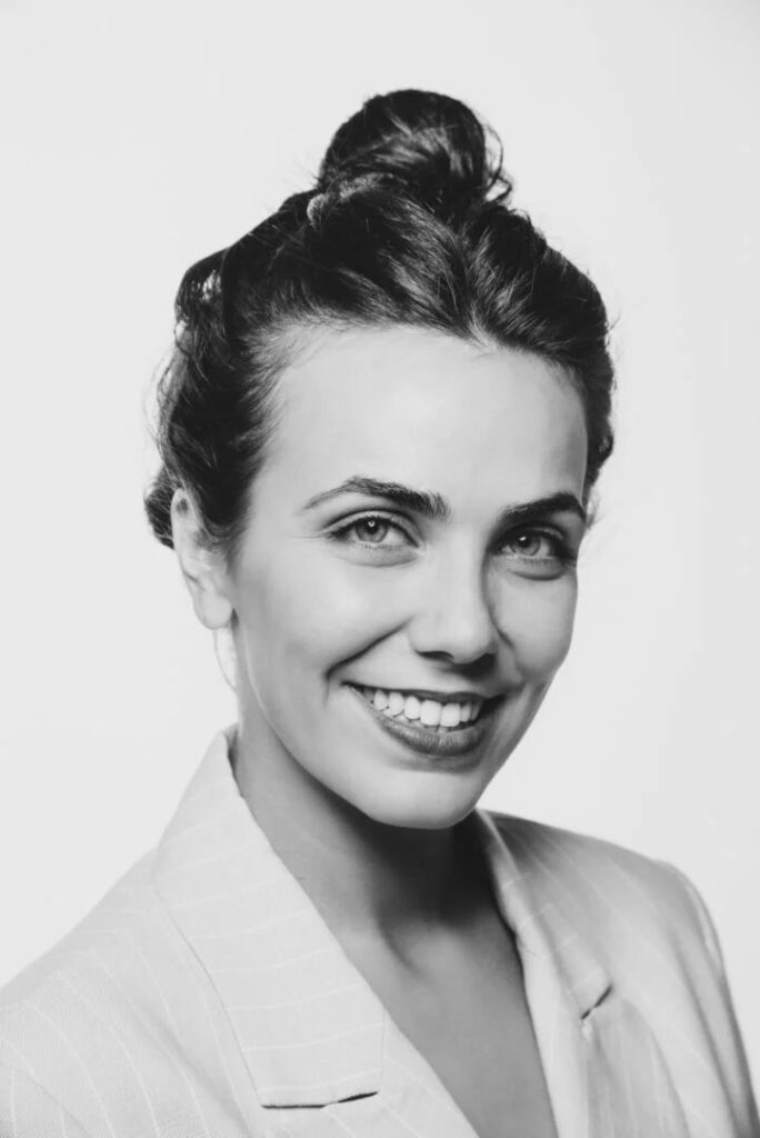 Headshot en blanco y negro de mujer sonriente con americana clara